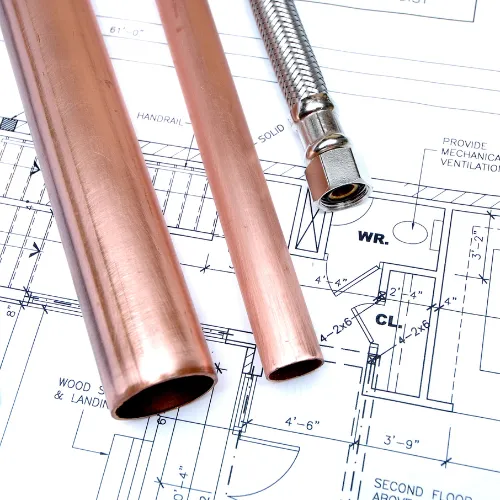 Plumber working on copper pipework beneath a kitchen sink