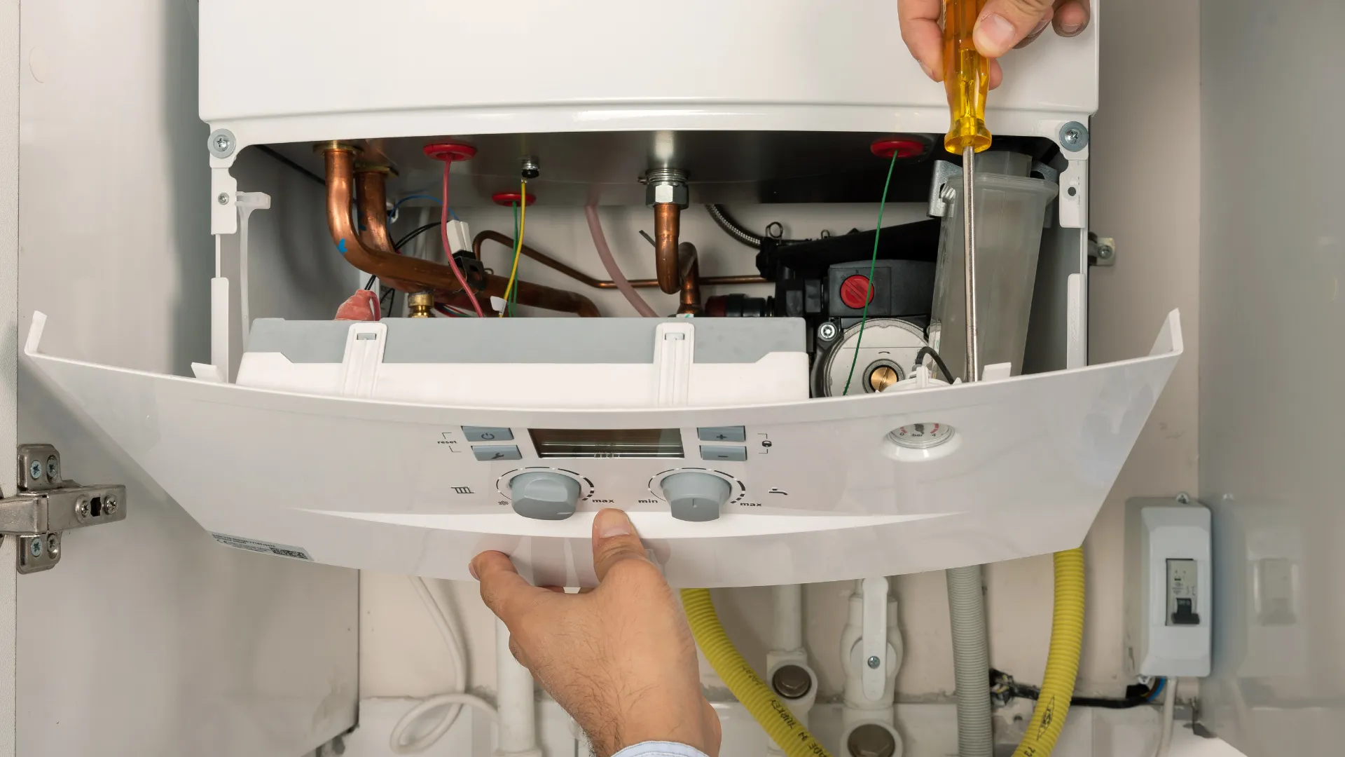 Plumbing engineer beside a boiler in a bright domestic kitchen